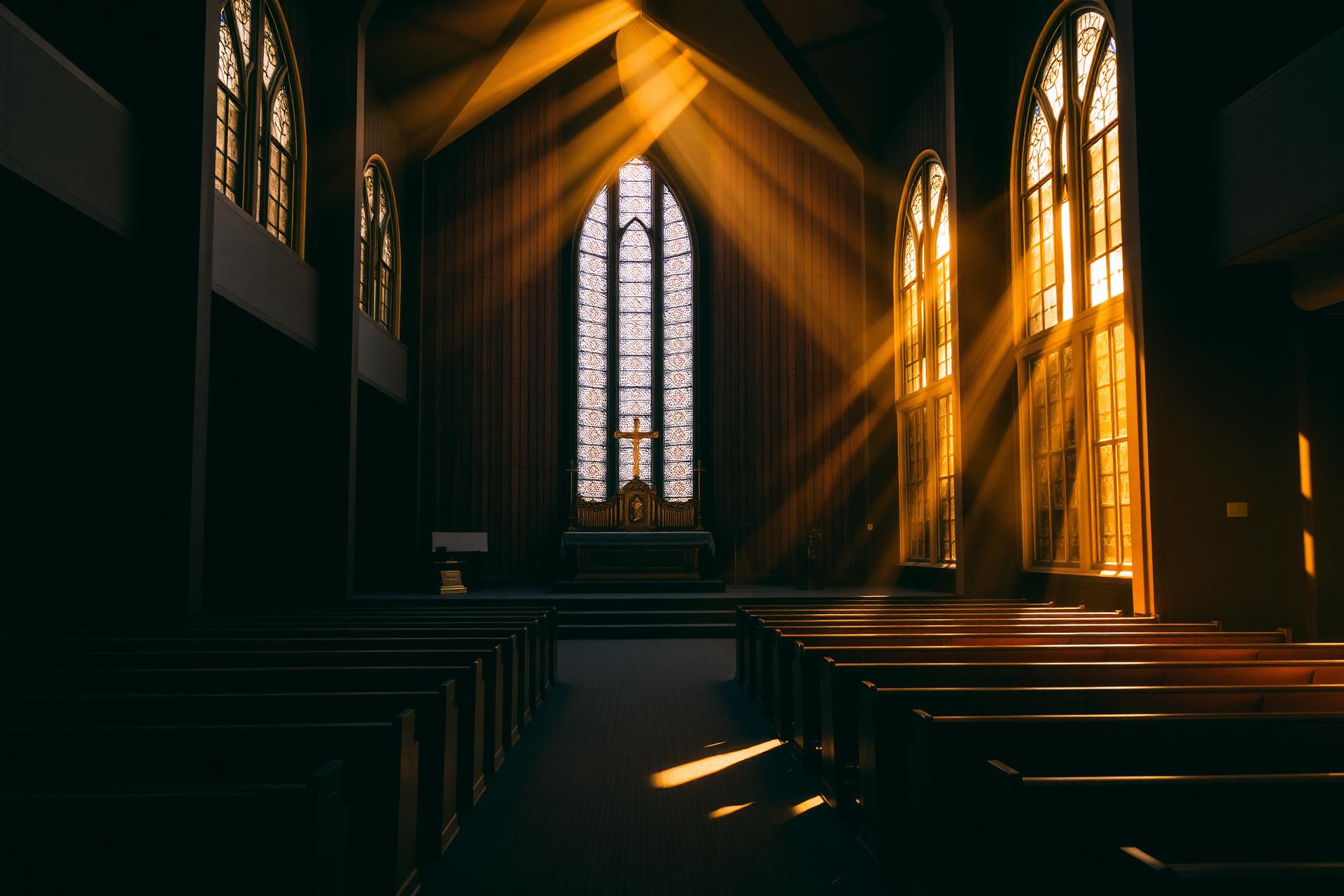 Sunlight streaming through stained glass windows of the church sanctuary